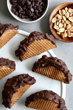 chocolate covered waffles on a plate next to bowls of nuts