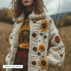 a woman standing in a field wearing a white coat with sunflowers on it