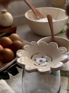 a white flower shaped bowl sitting on top of a table next to other bowls and utensils