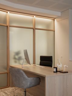 an office desk with a computer on top of it next to a chair and window