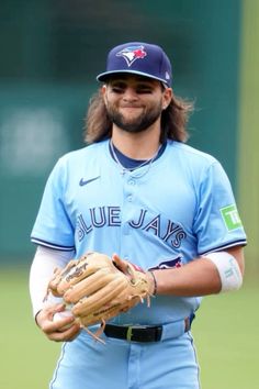 a man with long hair wearing a baseball uniform and holding a catchers mitt