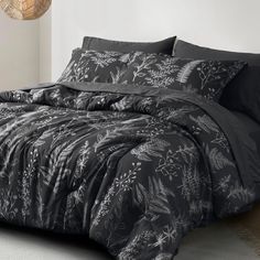 the comforter is made up with black and white floral designs on it, along with pillows