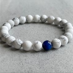 Features ~ 8mm White Howlite Beads. ~ 8mm Blue Tiger Eye Bead ~ Non-Fraying Stretchy Cord; Simply Slide Bracelet On And Off Wrist White Howlite - Howlite Is Predominantly A Calming Stone. It Will Aid In Sleeping, Calming The Overactive Mind, Eases Insomnia, Dreaming, Dream Retention And Stress Relief. Physically, It Calms The Whole Body And Releases Muscle Tension. It Also Eliminates Pain Brought About By Stress. Tiger Eye - A Stone Of Protection, Tiger Eye May Also Bring Good Luck To The Wearer White Gemstone Beads Casual Bracelet, Casual White Gemstone Beaded Bracelets, Casual White 8mm Bead Jewelry, Casual White Beaded Bracelets With Gemstone, White Casual Beaded Bracelets With Gemstone Beads, Casual White Beaded Bracelet With Gemstone Beads, Casual White Jewelry With 8mm Beads, Casual Blue Beaded Bracelets With 8mm Beads, Casual White Bracelets With Gemstone Beads