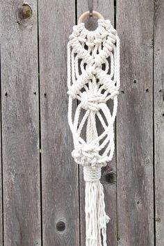 a white macrame hanging on a wooden fence