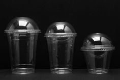 three plastic cups are lined up on a table with their lids down and one is empty