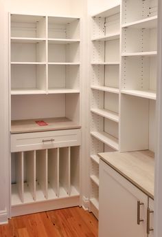 an empty pantry with white shelving and wood floors