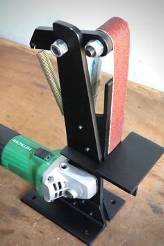 a sanding machine is sitting on a wooden table with a power tool attached to it