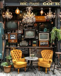 two yellow chairs sitting next to each other in front of a wall with old tvs on it