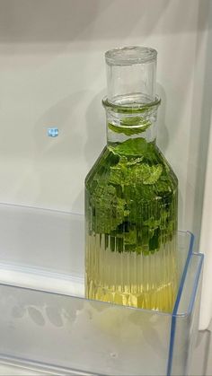 a glass bottle filled with green liquid on top of a shelf