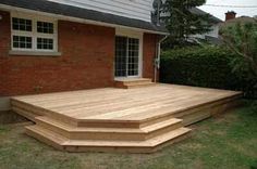 a wooden deck in front of a brick house