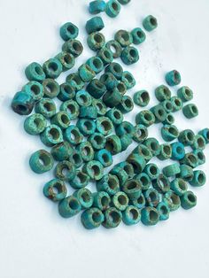 several pieces of turquoise green ceramic beads on a white surface with holes in the middle