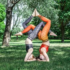 two women doing handstand in the park on their stomachs and arms together