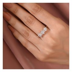 a woman's hand with a three stone diamond ring on her left hand and the other hand holding an engagement ring