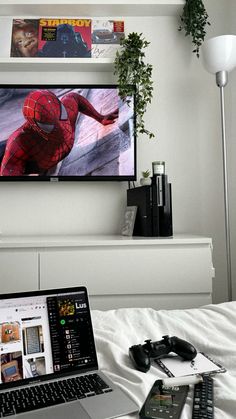 an open laptop computer sitting on top of a white bed next to a tv monitor