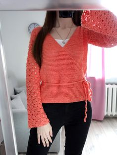 a woman is taking a selfie in the mirror wearing an orange sweater and black pants