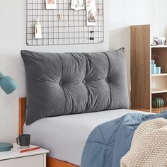 a bed with a gray headboard and blue comforter on it in a bedroom