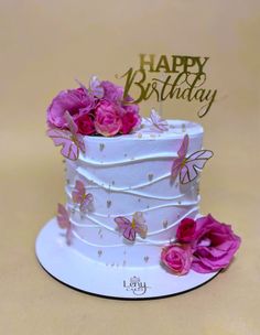 a white cake with pink flowers and butterflies on it's top tier is shown in front of a happy birthday card