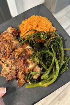 a plate with meat, broccoli and carrots on the table next to rice