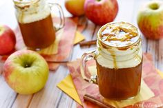 two mugs filled with caramel, apple cider and whipped cream on top of napkins