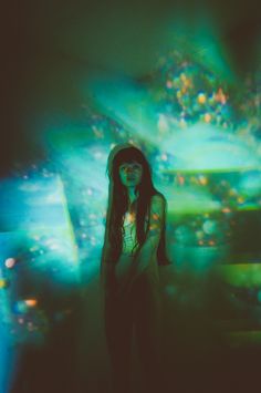 a woman is standing in front of a large screen with colorful lights on the wall