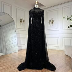 a black evening gown on display in a room with white walls and wood flooring