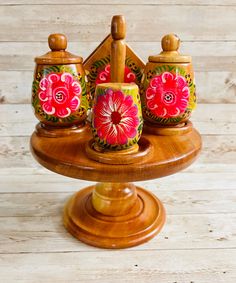 three wooden containers with painted flowers on them are sitting on a small stand in front of a wood wall