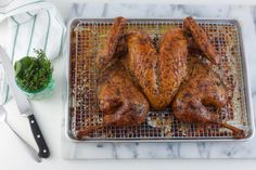 a whole chicken sitting on top of a cooling rack next to a knife and fork