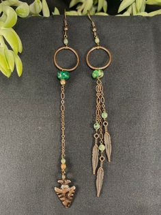 Inspired by elements of the forest, these asymmetrical earrings are the perfect unique complement to your aesthetic. The arrowhead brass charm with the brass feather charms creates a beautiful flow with a nice pop of green and jade. Green Bohemian Jewelry With Charms, Bohemian Dangle Charm Earrings, Bohemian Dangle Earrings With Charms, Bohemian Green Earrings With Dangling Charms, Green Bohemian Earrings With Dangling Charms, Green Rustic Dangle Earrings, Green Rustic Dangle Jewelry, Rustic Green Dangle Earrings, Rustic Green Dangle Jewelry