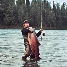 a man holding a fish while standing in the water