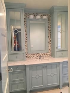 a bathroom with blue cabinets and a white sink under a large mirror in the corner