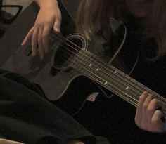 a woman is playing an acoustic guitar in the dark