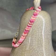 a pink and white beaded necklace sitting on top of a mannequin head