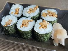 four sushi rolls on a plate with chopsticks and garnishes