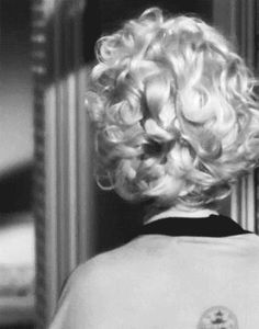 the back of a woman's head with curly blonde hair in a black and white photo