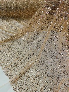 gold and silver sequins on white fabric with black dots in the center, closeup