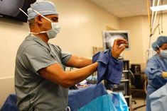 two doctors in scrubs and masks are doing surgery