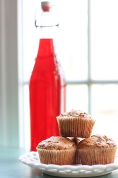 three muffins on a plate next to a bottle of soda