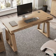 a wooden desk with a computer monitor and keyboard on it in front of a window