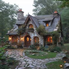 a stone house in the middle of a forest with lights on it's windows