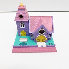 there is a small toy house with a pink roof and yellow doors on the front