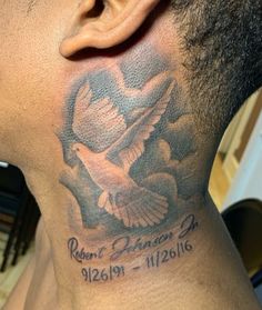 the back of a man's neck with a dove and date tattoo on it