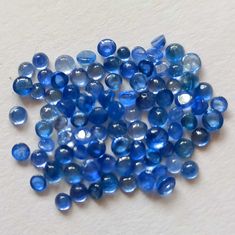 blue glass beads are scattered on a white surface