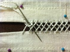 a pair of scissors is on the side of a piece of fabric with stitching