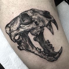 a black and white photo of a skull on the thigh with an arrow in it