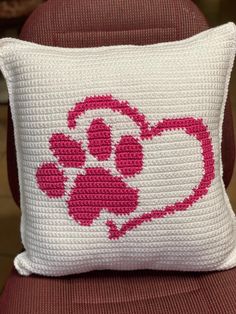 a crocheted pillow with a dog's paw and heart on the front