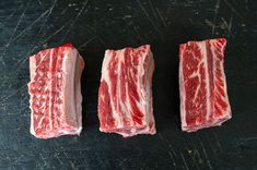 three pieces of raw meat sitting on top of a cutting board