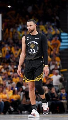 a man in black and yellow uniform standing on a basketball court with his foot up