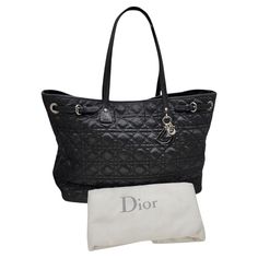 This Christian Dior Cannage Panarea Medium Tote was made in Italy and it is finely crafted of black coated canvas with Cannage pattern embroidery. It features a magnetic snap closure that opens up to a very spacious black canvas interior with one zip pocket and two slip pockets. Light gold-tone DIOR letter charms adorn the front, which adds some bling to this glamorous bag! Brand: Christian Dior Material: Black Cannage Quilted Coated Canvas Date/Authenticity Code: 01-RU-0049 Production Year: 200 Medium Tote, Shopper Tote, Letter Charms, Black Canvas, Lady Dior, Black Coat, Fashion Handbags, Christian Dior, Vintage Dior