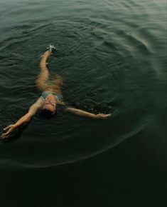 a woman floating in the water with her legs spread out and head above the water