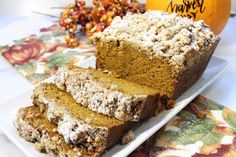 a white plate topped with slices of cake next to an orange pumpkin and other autumn decorations